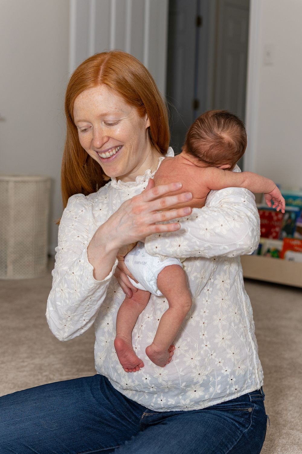 Joyful moment captured as parent holds newborn baby while wearing white eyelet lace top during a newborn portrait photo shoot in Sudbury, MA