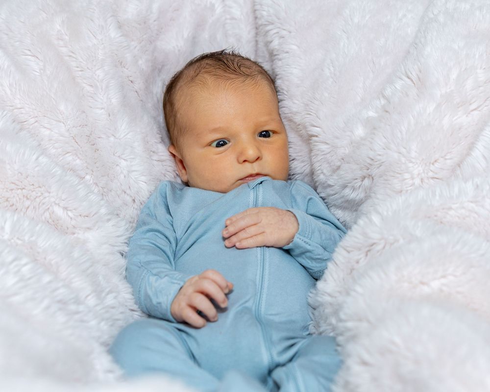 Black and white portrait of infant in soft clothing on textured blanket during a newborn portrait photo shoot in Sudbury, MA outside Boston,