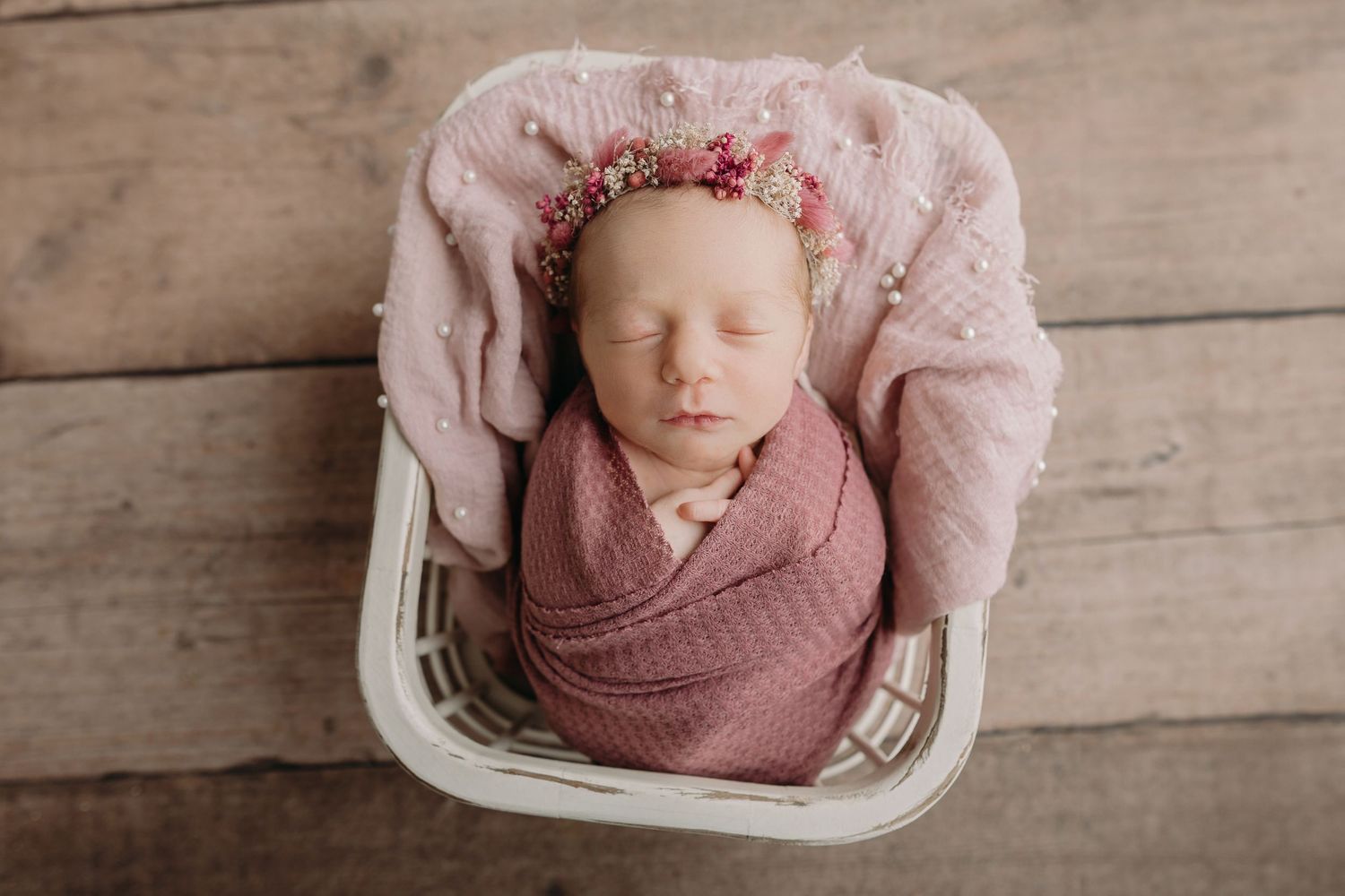 A baby in a pink tulle dress celebrates their first birthday with balloon decorations in soft pink, white and rose gold.