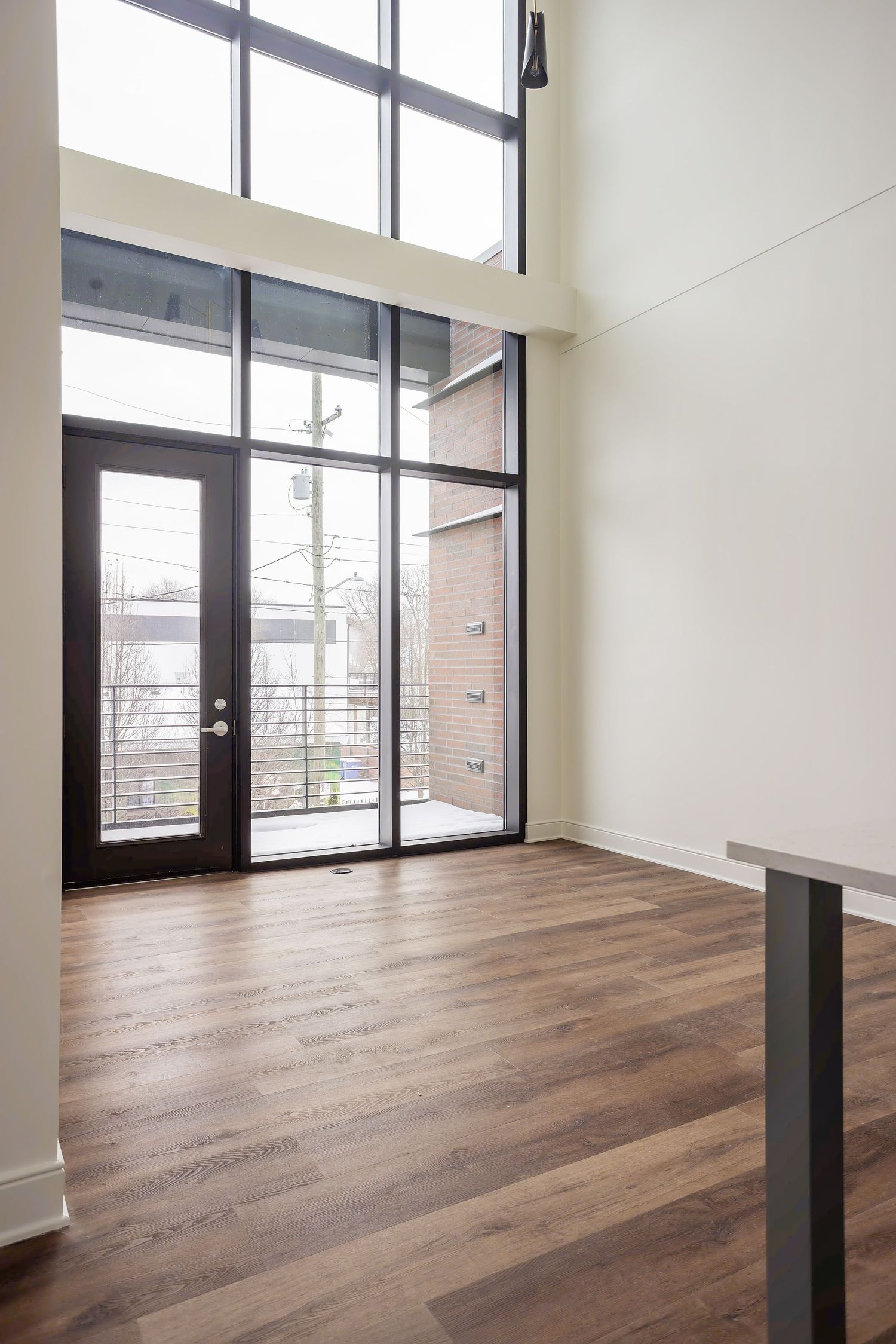 Modern entryway with floor-to-ceiling windows, glass door, and hardwood flooring.