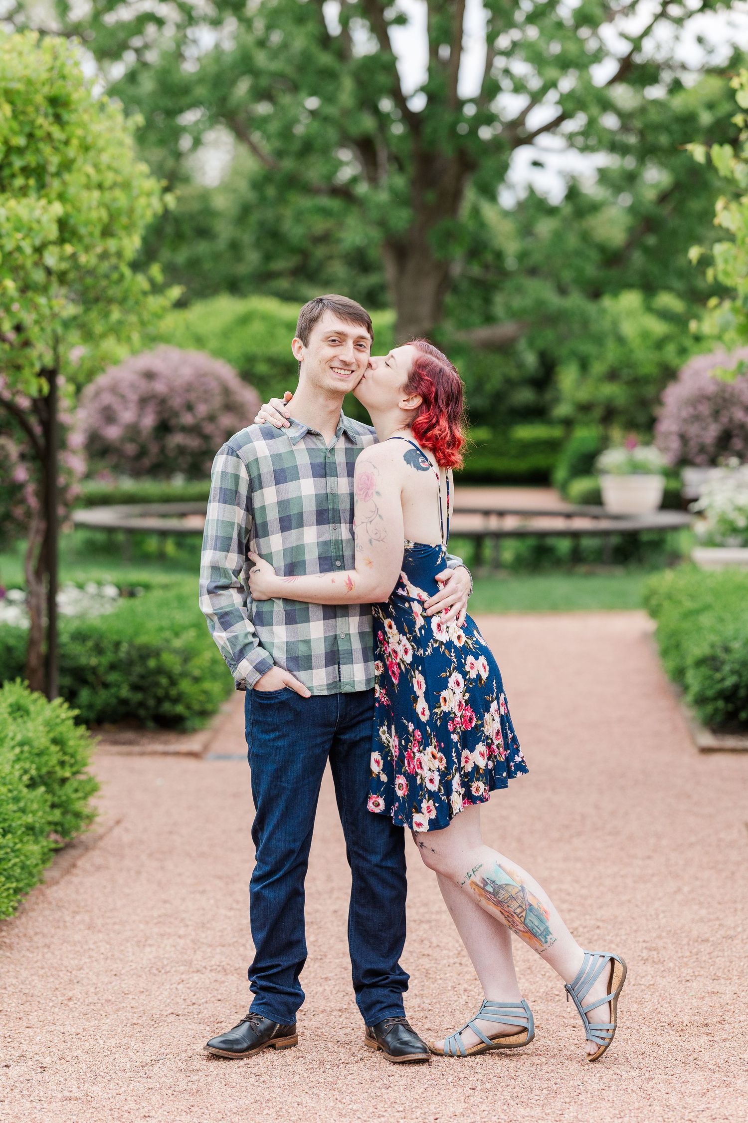 A couple embraces on a garden path surrounded by green landscaping and blooming flowers on a spring day at Cantigny Park