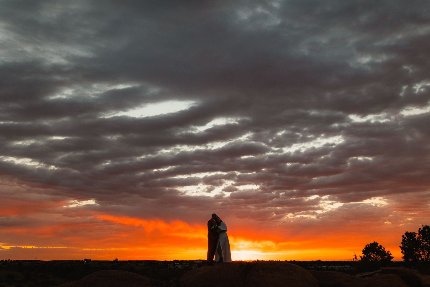 A silhouetted lighthouse stands against a dramatic sunset sky with vibrant orange clouds.