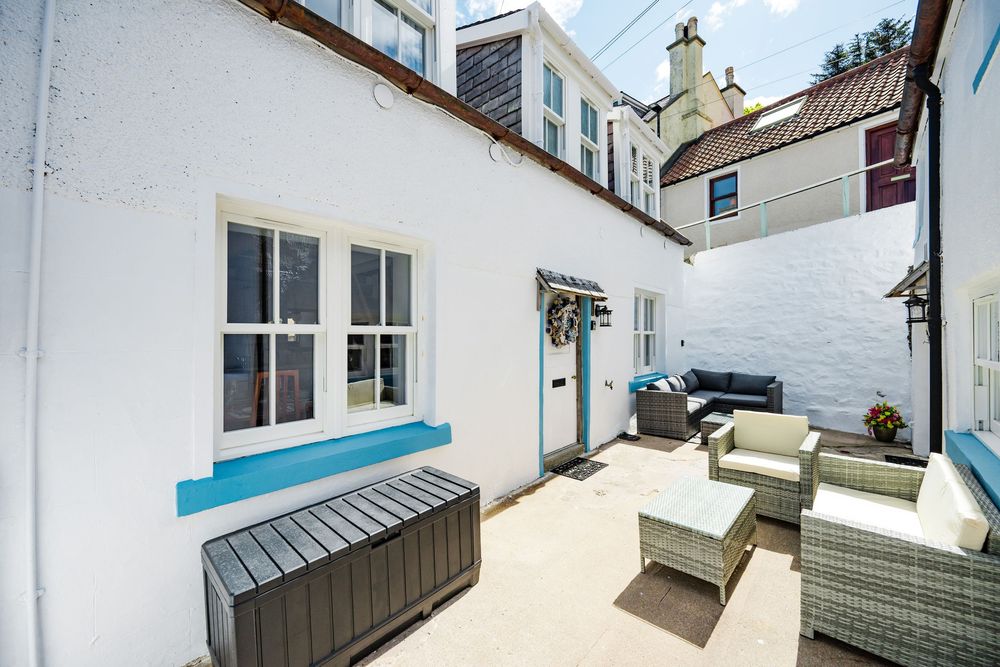 Modern outdoor terrace with comfortable patio furniture and white walls in a coastal property.