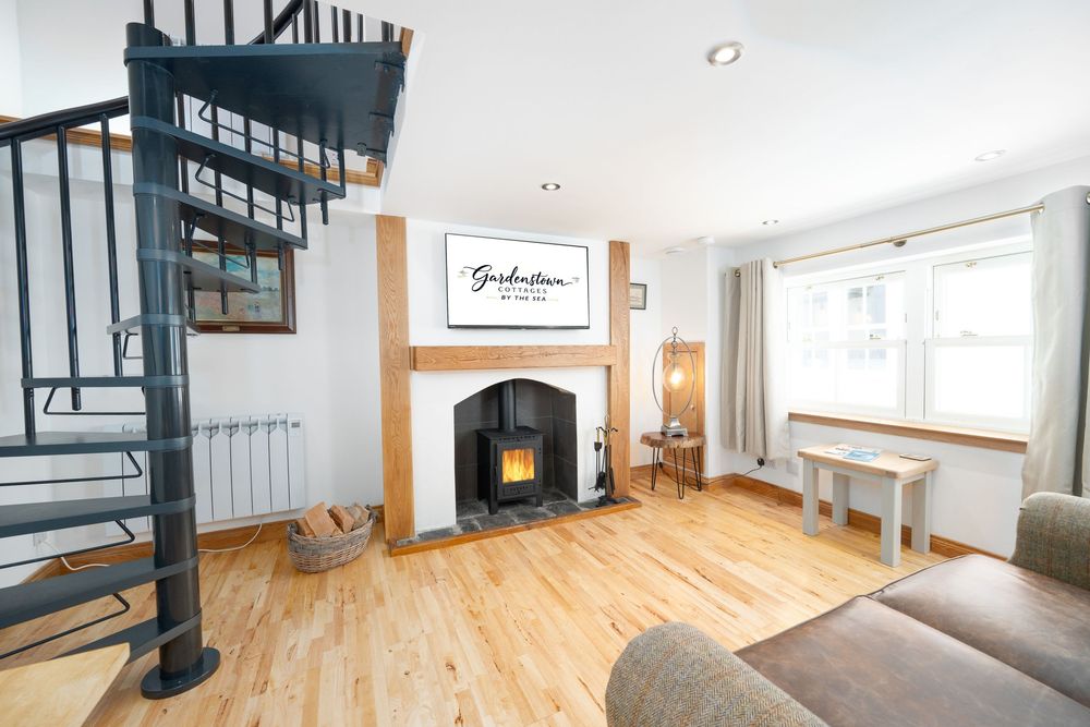 Living room with spiral staircase, fireplace, wood floors and large window features modern yet cozy interior design.