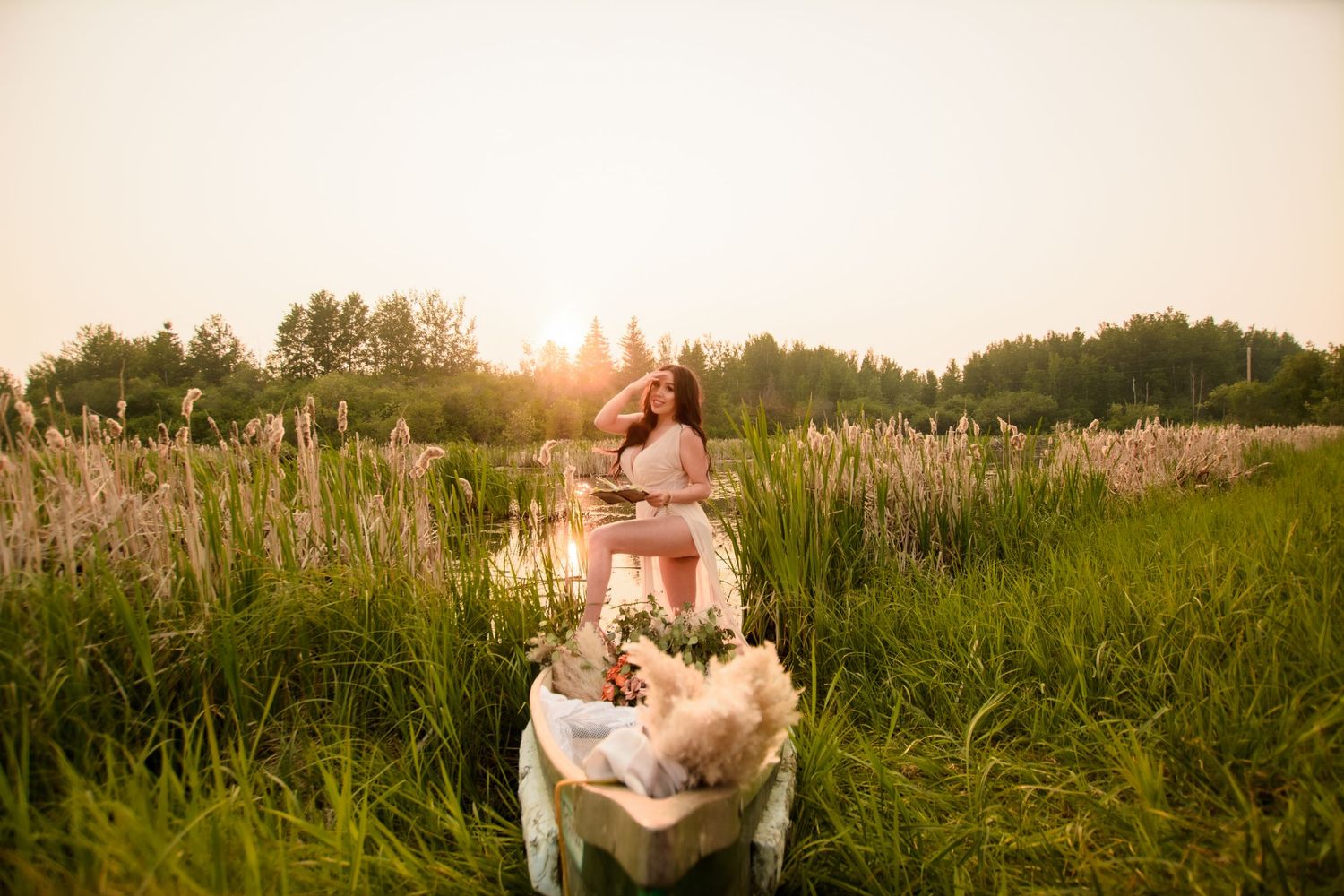 A romantic couple sits together in a golden meadow during sunset while surrounded by wildflowers and tall grass.