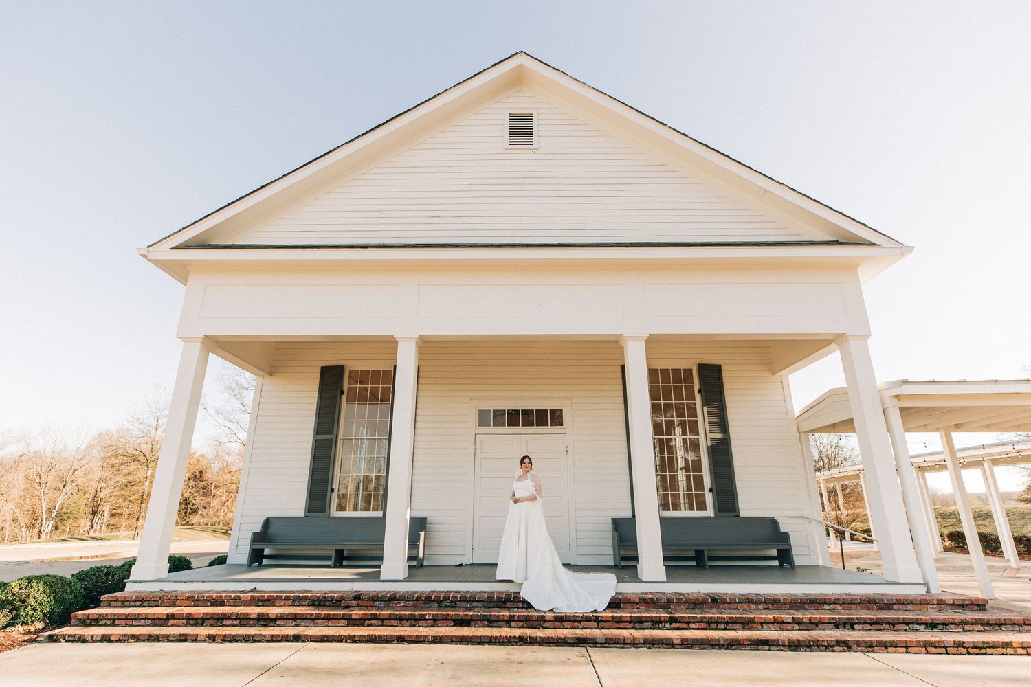White modern farmhouse venue with classic columns and a wraparound porch captured in different angles at sunset.