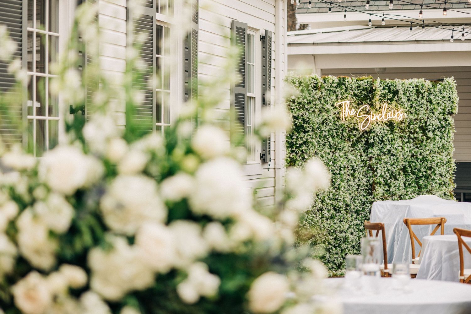 Elegant white floral wedding reception decor with crystal chandelier lighting in a glass conservatory venue.