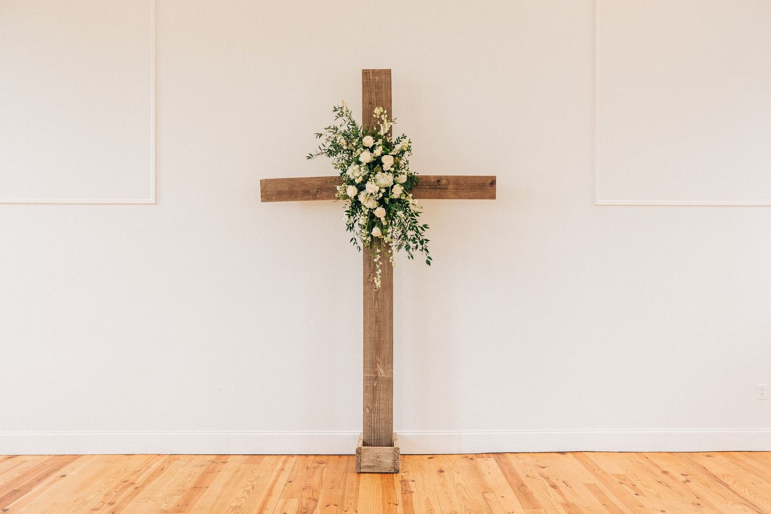 Two wooden crosses mounted against white walls create a minimalist religious backdrop.