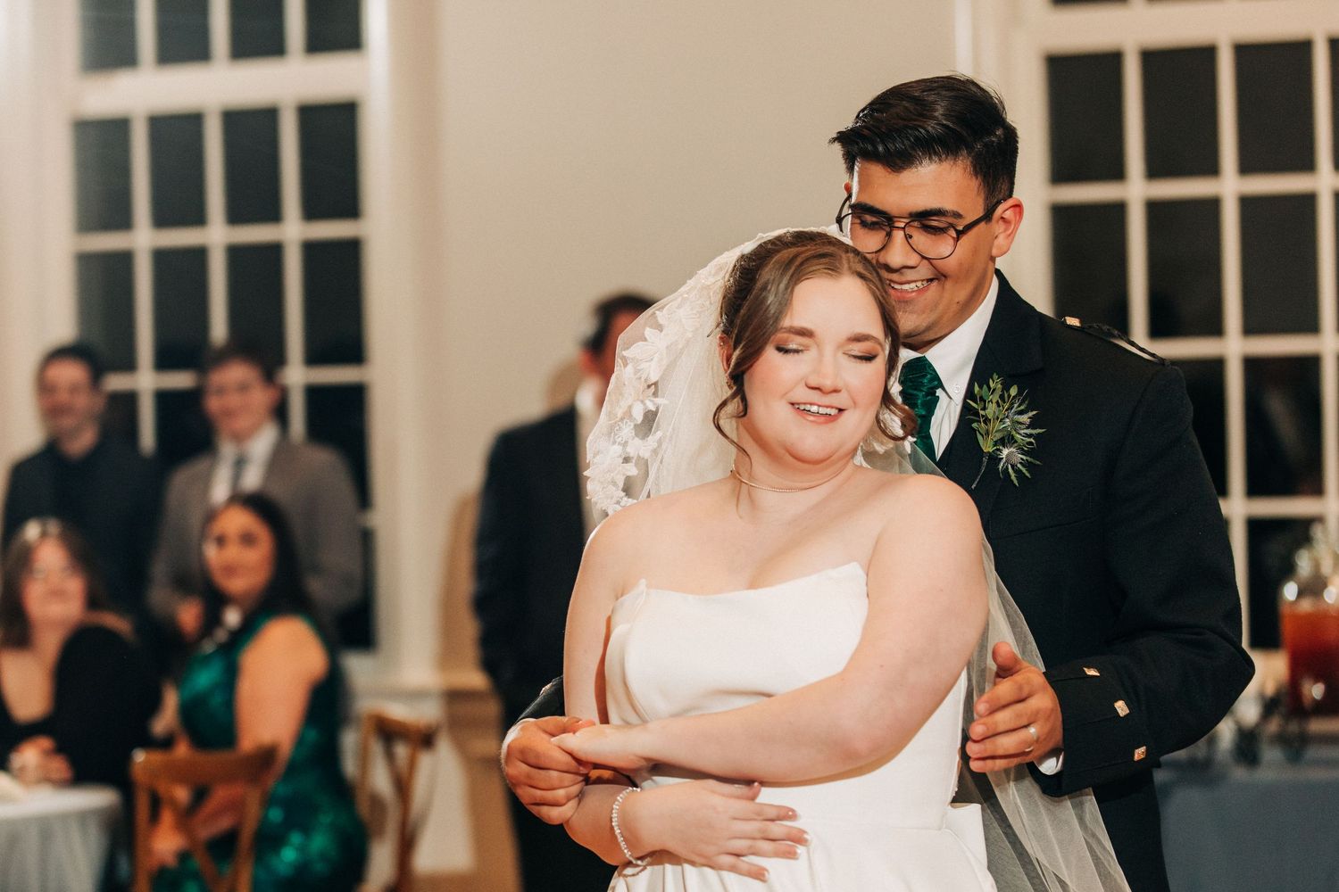A couple shares their first dance as newlyweds at their wedding reception in an elegant venue with white columns.