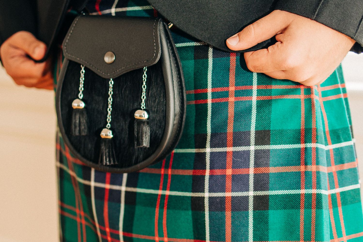 Two people wearing matching green and red plaid kilts and formal black jackets perform at a Scottish event.