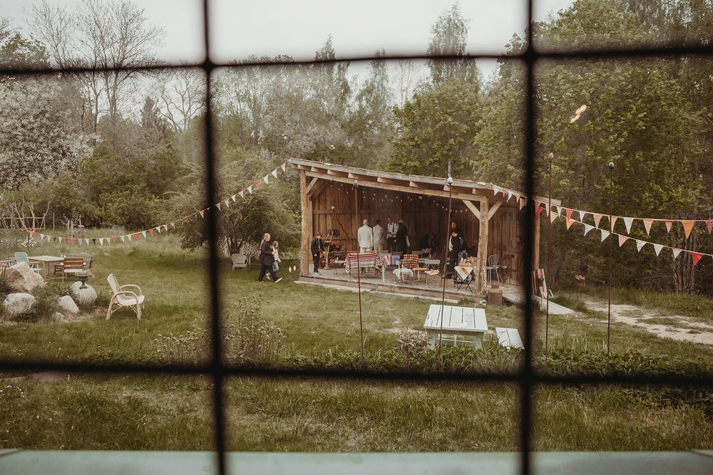 Träscen i trädgård med dekorationer för borgerlig vigsel, omgiven av grönska och blommor, bröllopsplats på Borkhult Lapphem i Åtvidaberg.