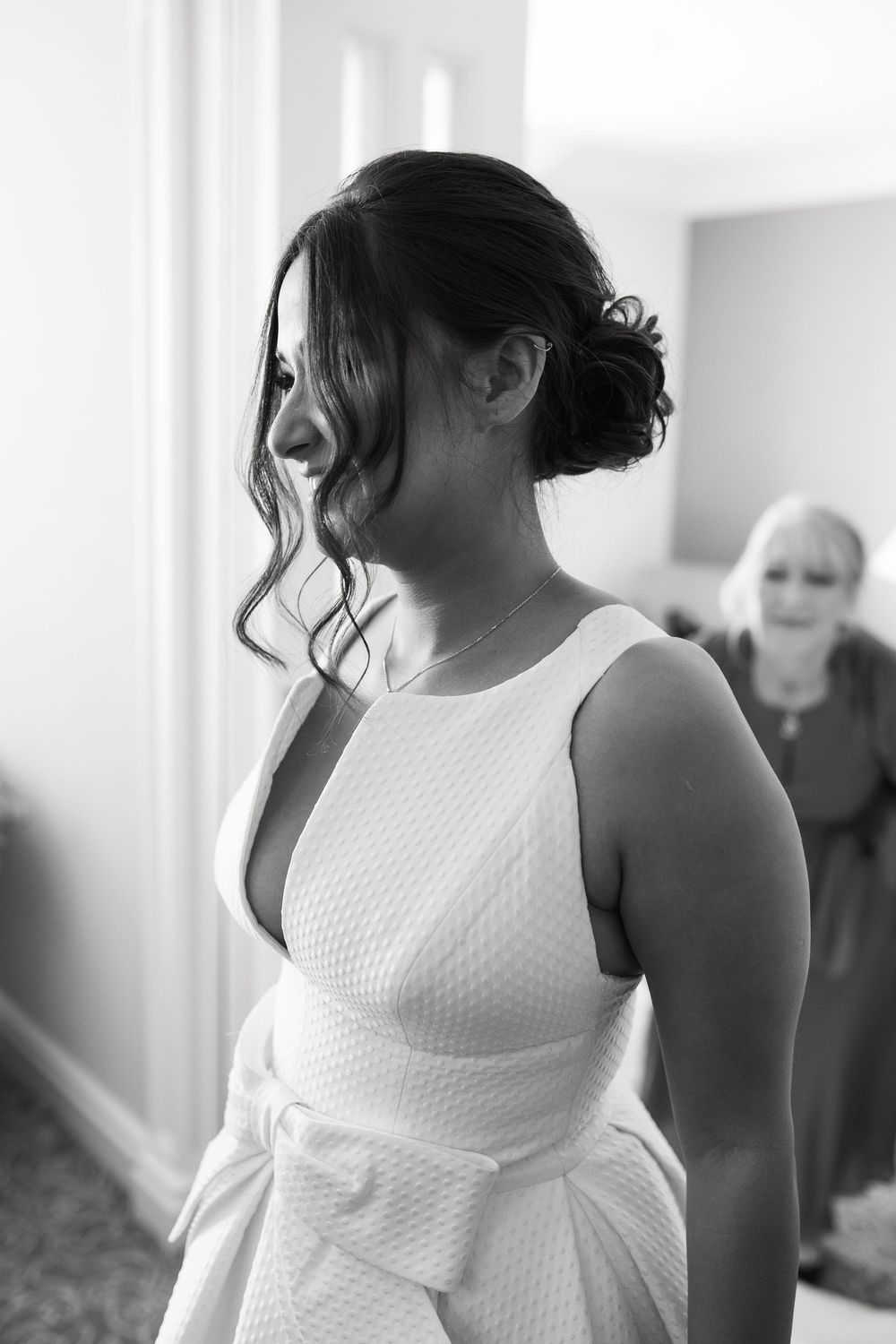 Side profile of bride in textured white wedding dress with elegant updo hairstyle.