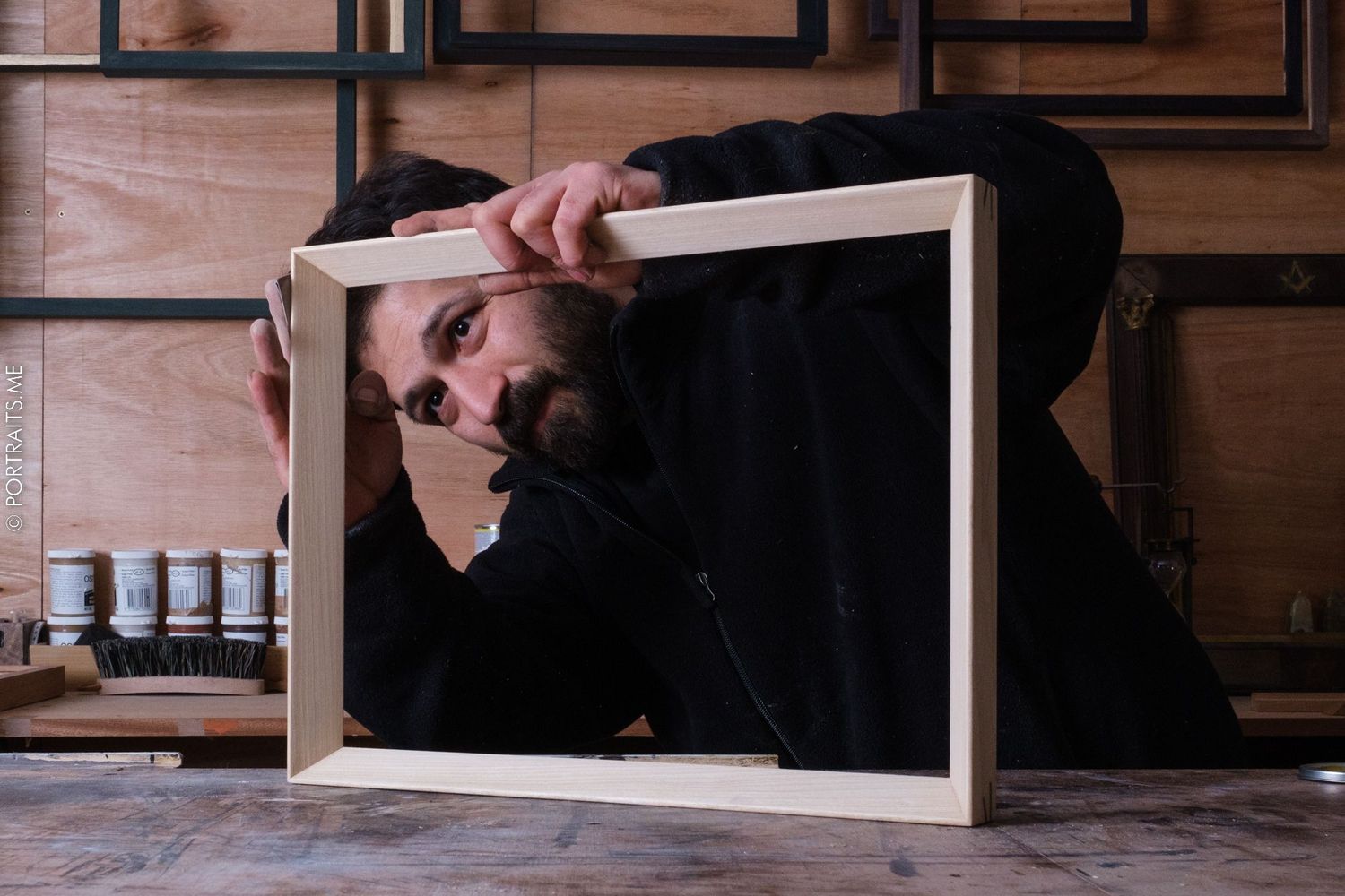 Craftsperson working on wooden frame construction in workshop setting.