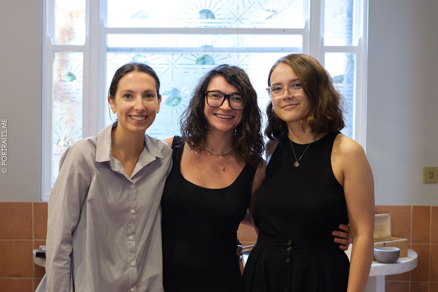 Three colleagues gather together for a friendly photo by a bright window.