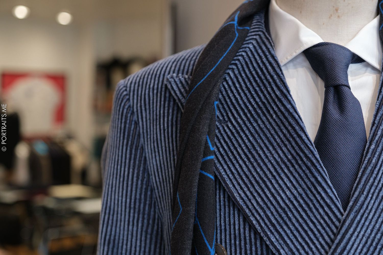 Close-up of pinstriped blue suit jacket with tie showing professional tailoring details.