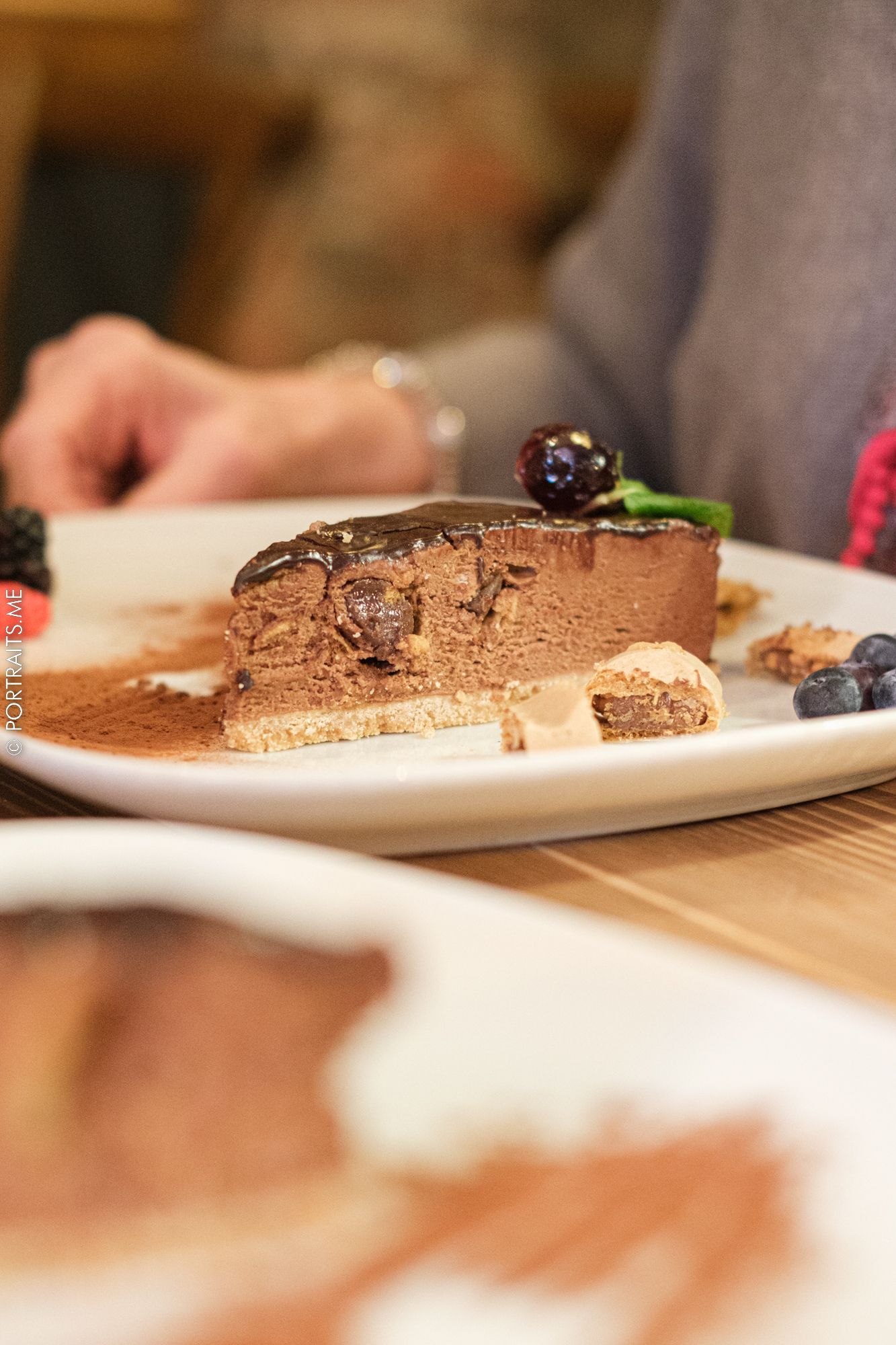 A slice of rich chocolate mousse cake garnished with fresh berries on a white plate.