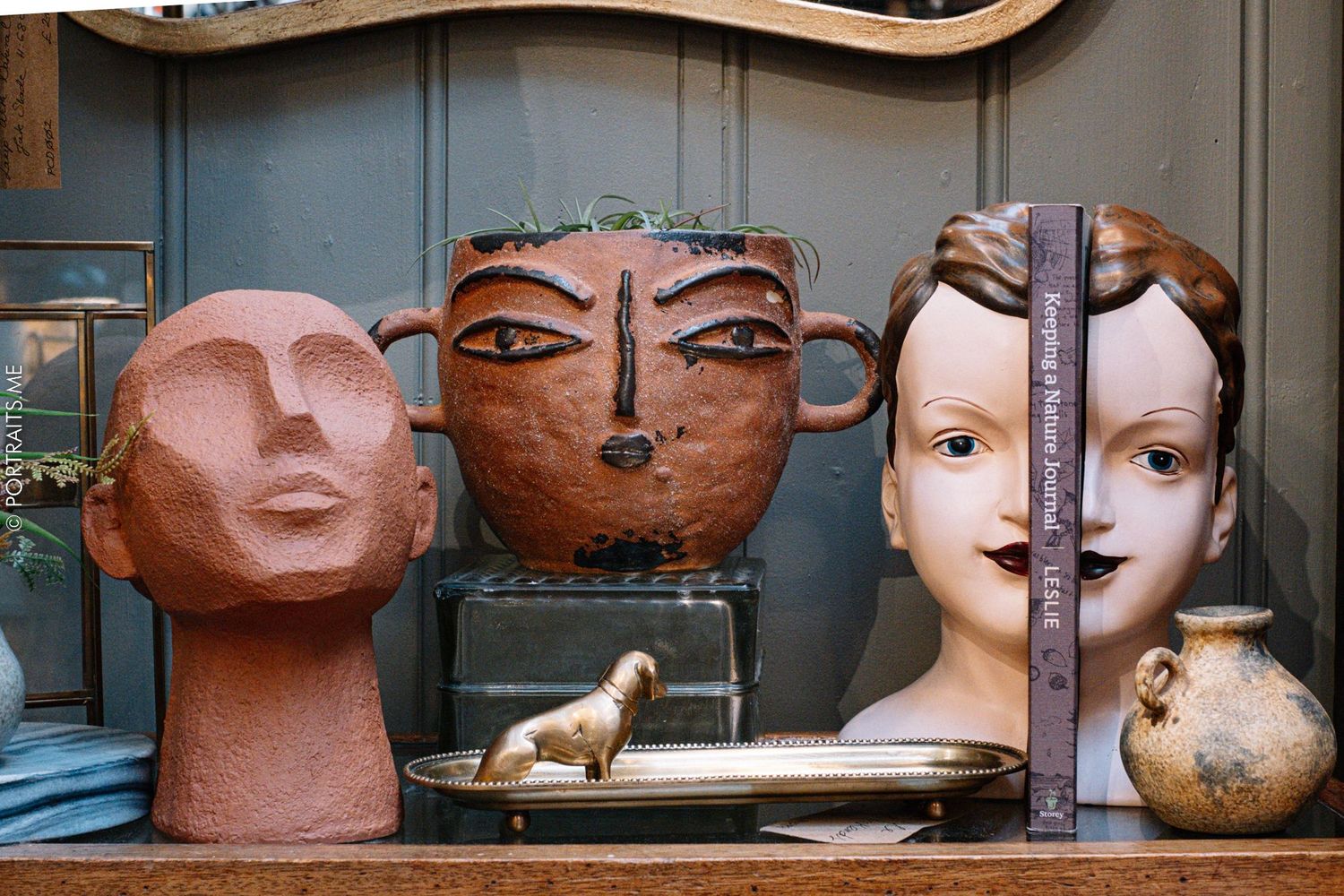 Decorative ceramic head sculptures in various colors displayed on a shelf.
