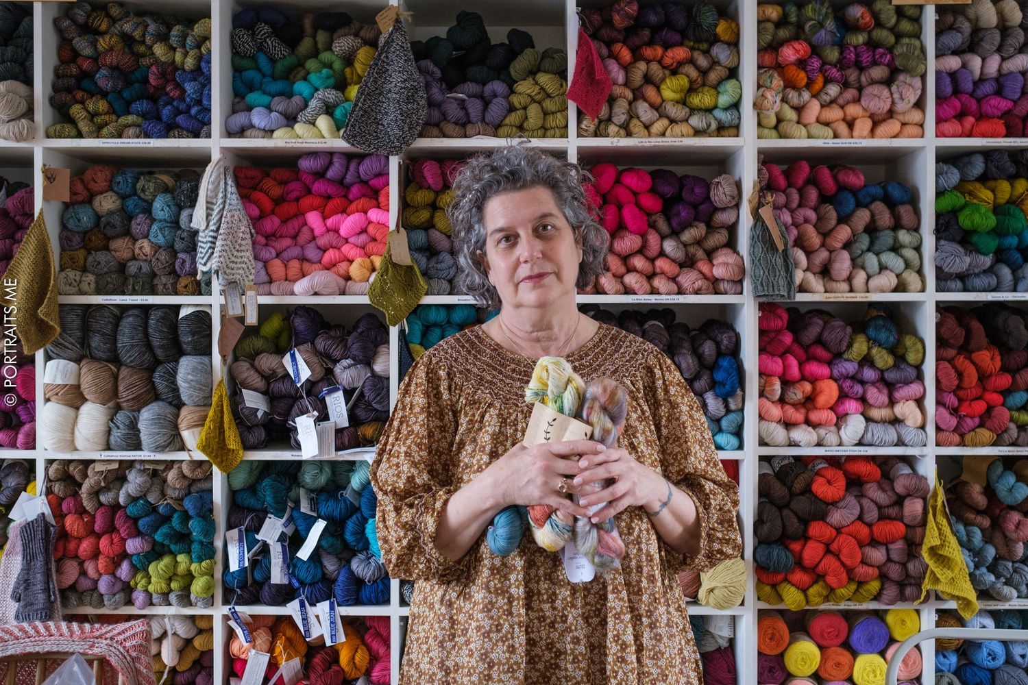 Person standing in front of colorful wall display of yarn and craft supplies.