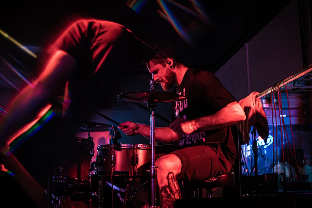 Musician illuminated in red light performing on stage.