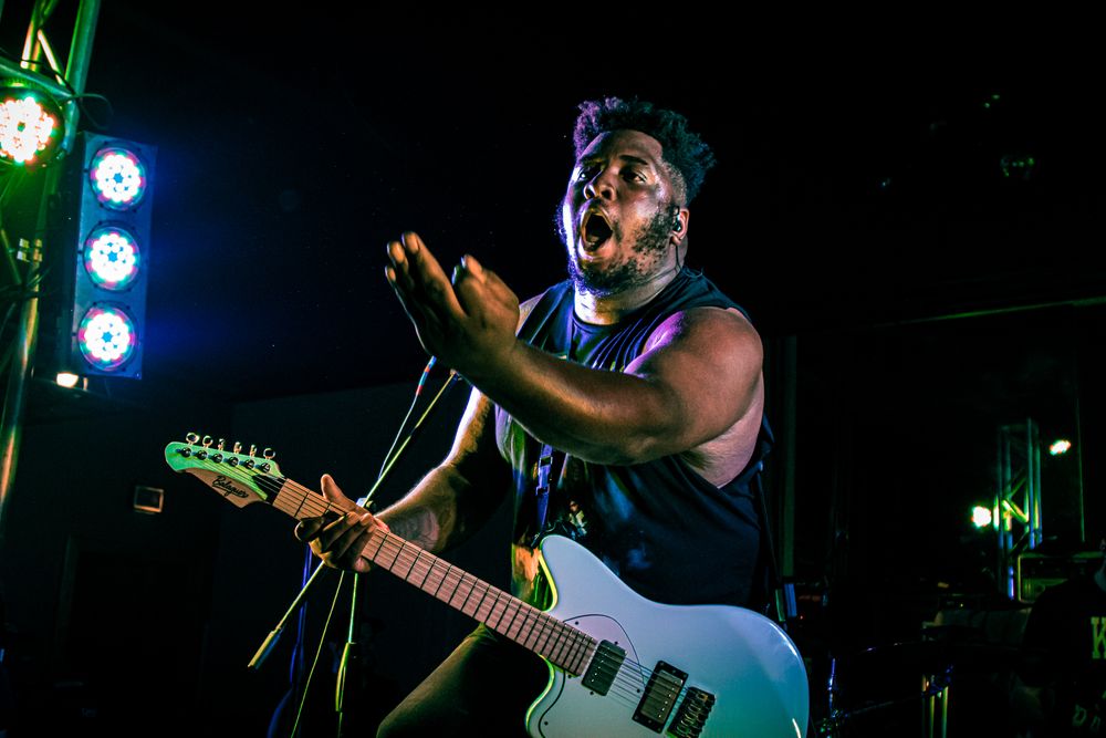 Electric guitarist performing passionately under blue stage lights.