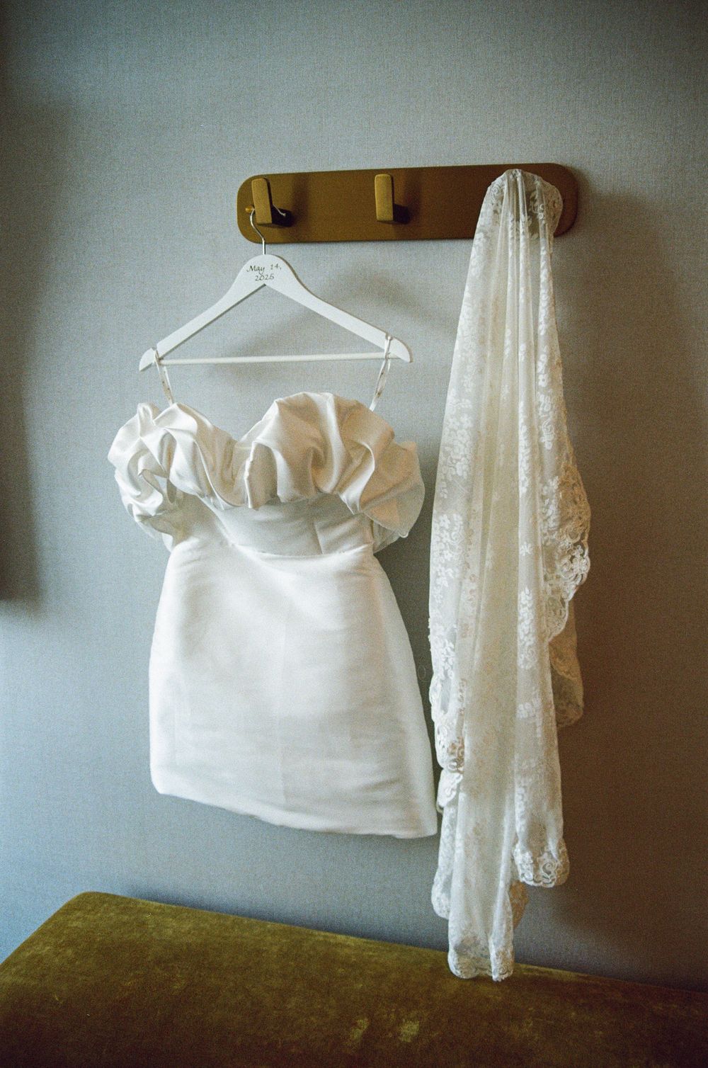 White clothing on hangers displayed against a dark wall with a rustic green surface visible below.