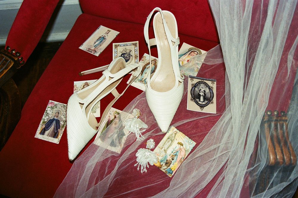 White wedding shoes with price tags and tulle fabric arranged in a bridal display against a red background.