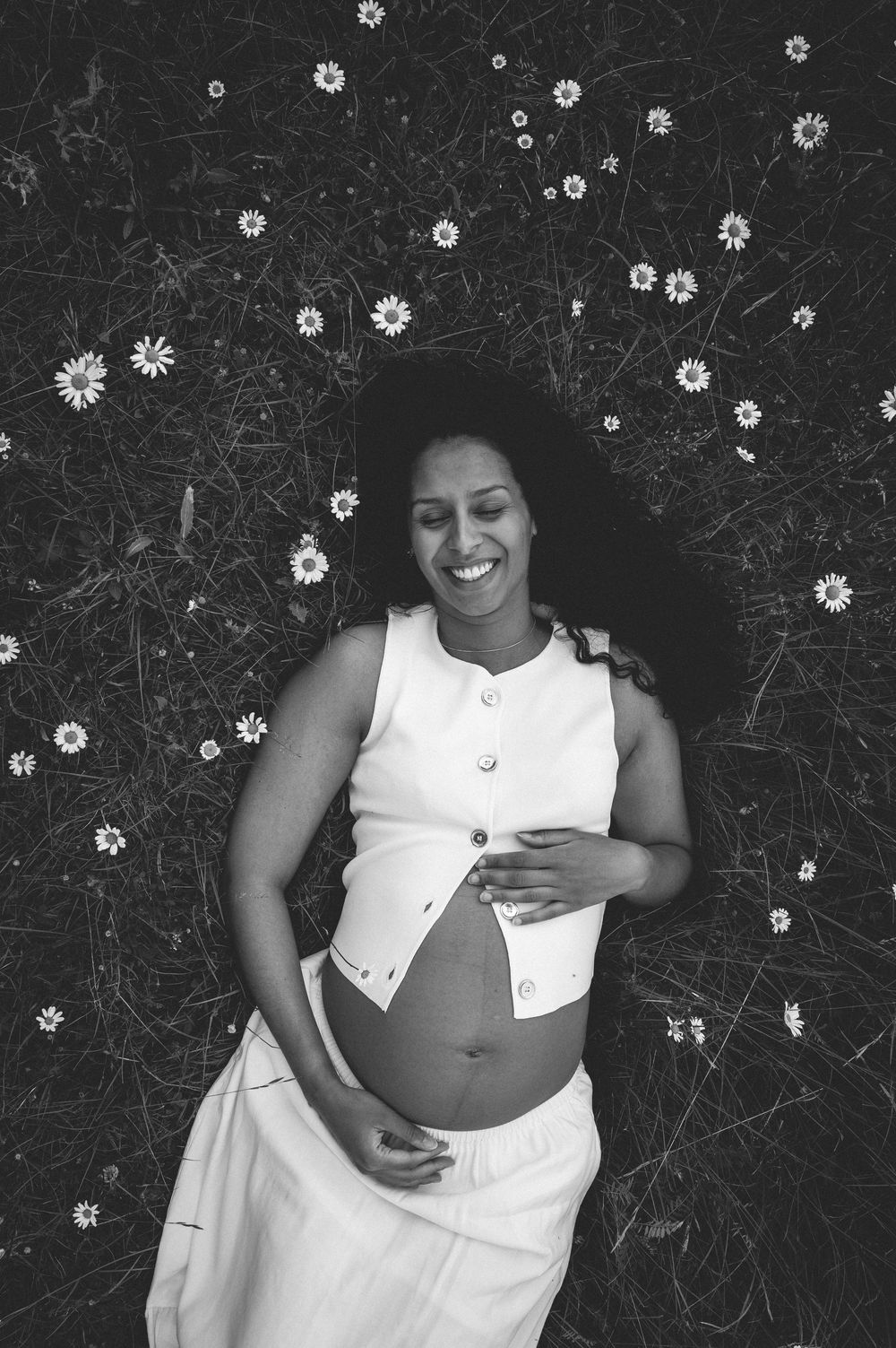 Multiple shots capture a woman reclining in a white dress amid scattered wildflowers in monochrome.