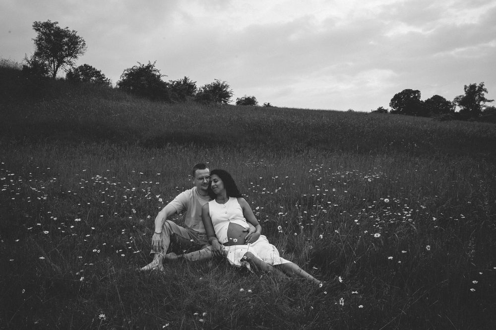 A romantic black and white scene of a couple resting together in a field of wildflowers.