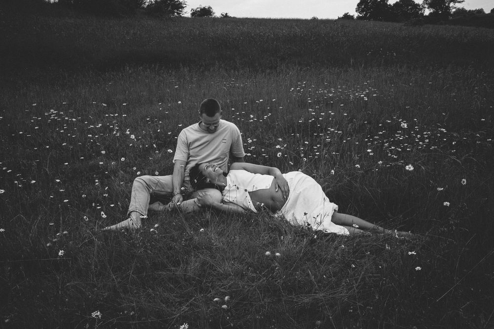 A couple lounges together in a meadow of wildflowers on a peaceful summer afternoon.