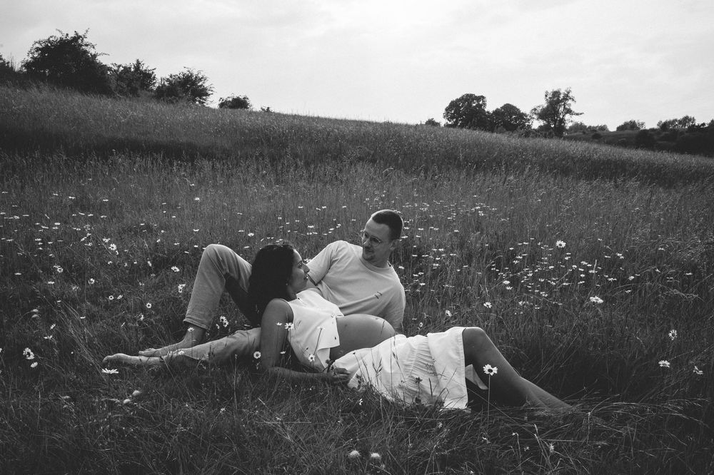 A sequence of vintage black and white photographs showing a couple lying in a daisy-filled meadow.