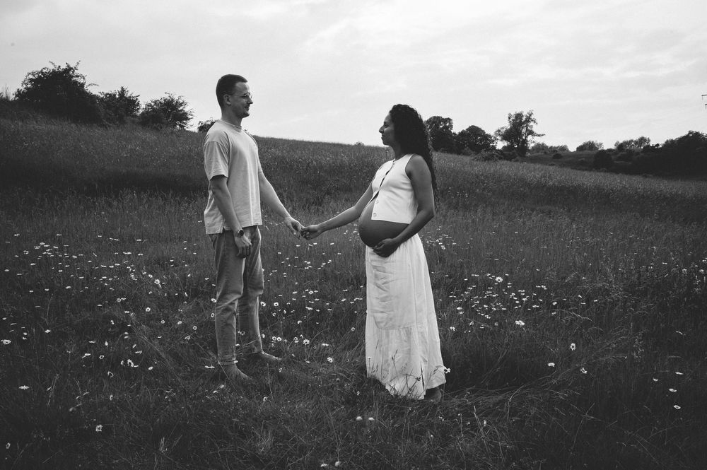 A joyful couple walks through a blooming meadow on a warm summer day.