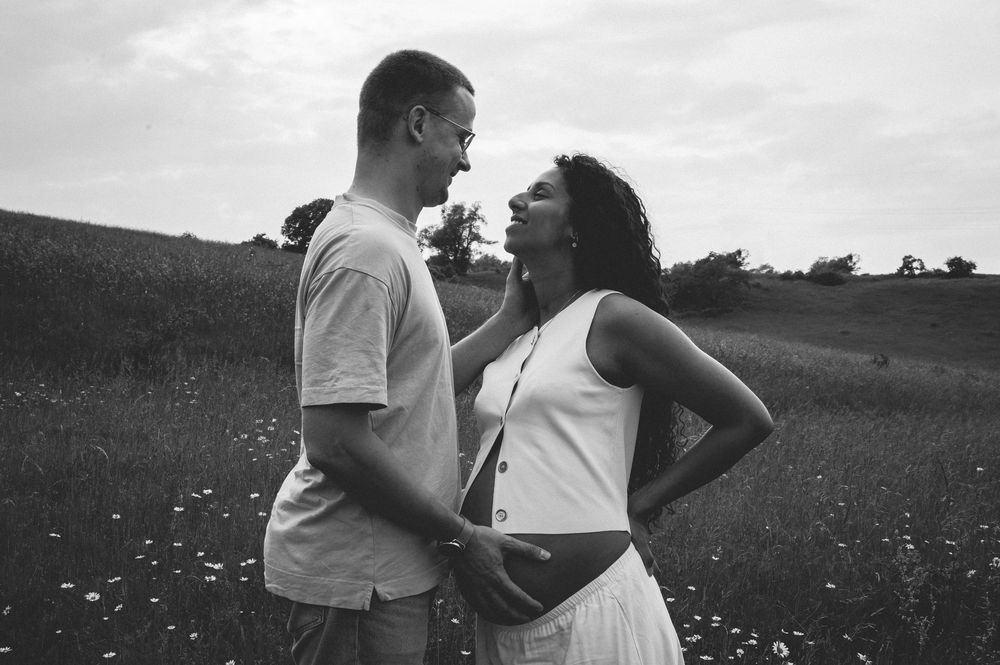 A couple shares a playful moment together in a black and white photo taken in a field of wildflowers.