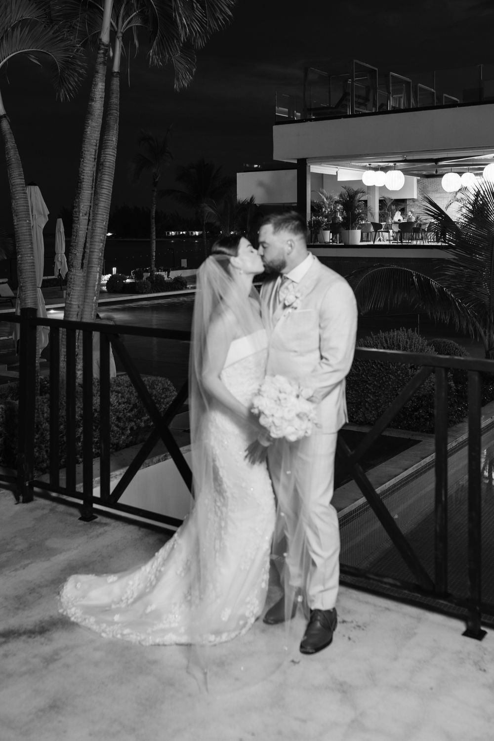 A romantic black and white photo sequence of a couple in wedding attire outside at night sharing tender moments.
