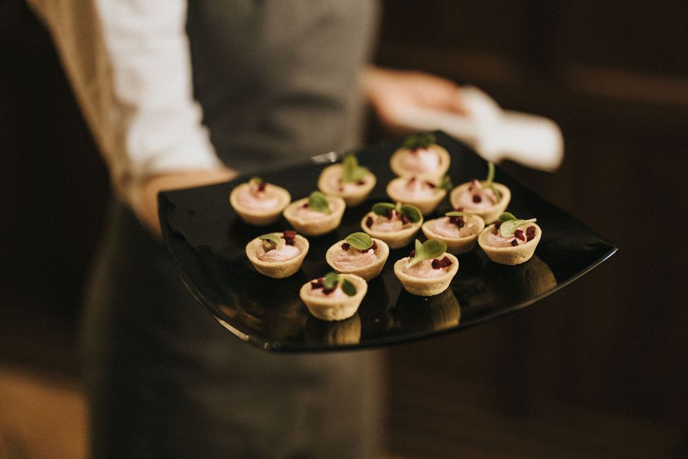 A tray of bite-sized catering appetizers arranged on elegant black plates at an upscale event.