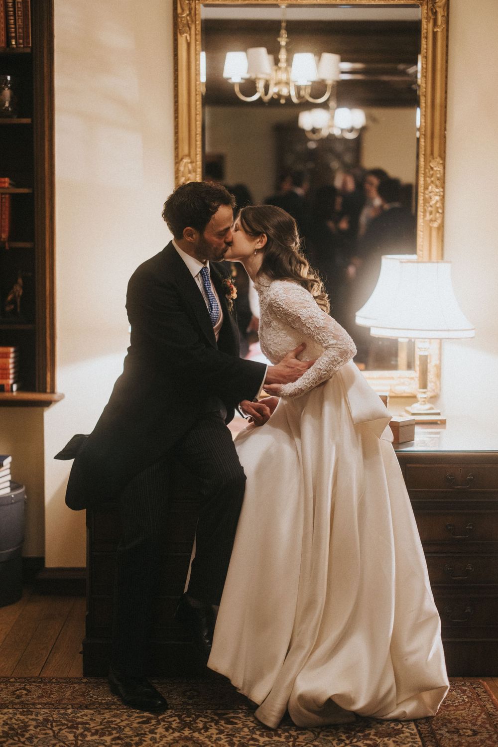 A romantic couple shares an intimate moment in a dimly lit room, with her wearing an elegant white wedding gown.