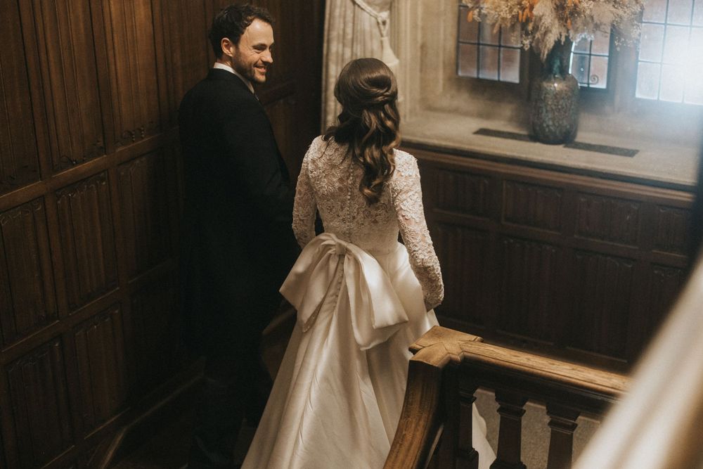 A couple embraces in a romantic wooden church setting filled with natural light through stained glass windows.