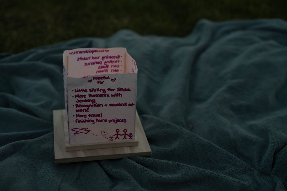 Pink and purple post-it notes with handwritten messages arranged in a line against a dark fabric background.