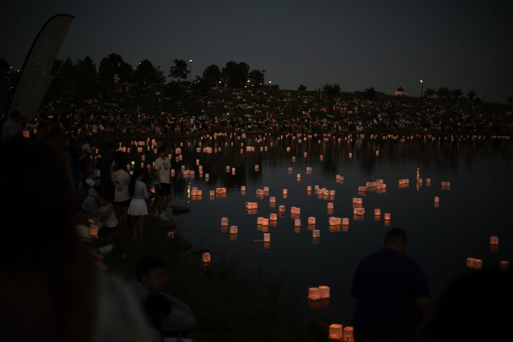 Paper lanterns glowing softly in a nighttime gathering illuminate multiple rows at the National Memorial Cemetery of the Pacific.