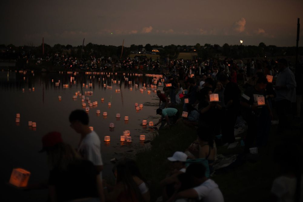 Paper lanterns illuminate the shoreline as spectators gather at dusk for a traditional lantern festival.
