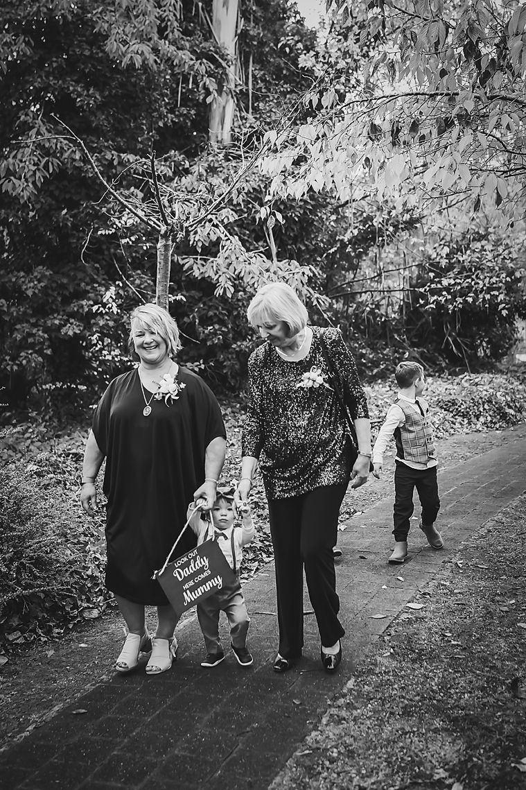 Black and white candid shots of children holding hands while walking along an outdoor garden path.