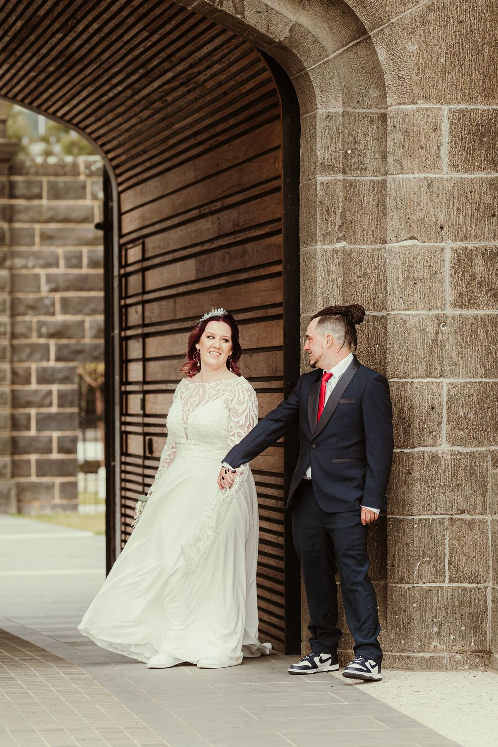 A happy couple posing in a series of five photos in front of stone archways during their wedding photoshoot.