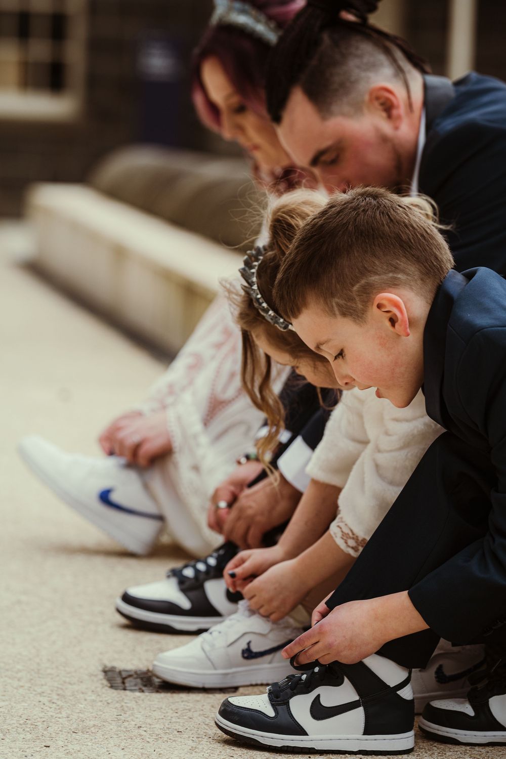 A group wearing matching Nike Air Jordan sneakers sits on steps while tying their shoelaces.