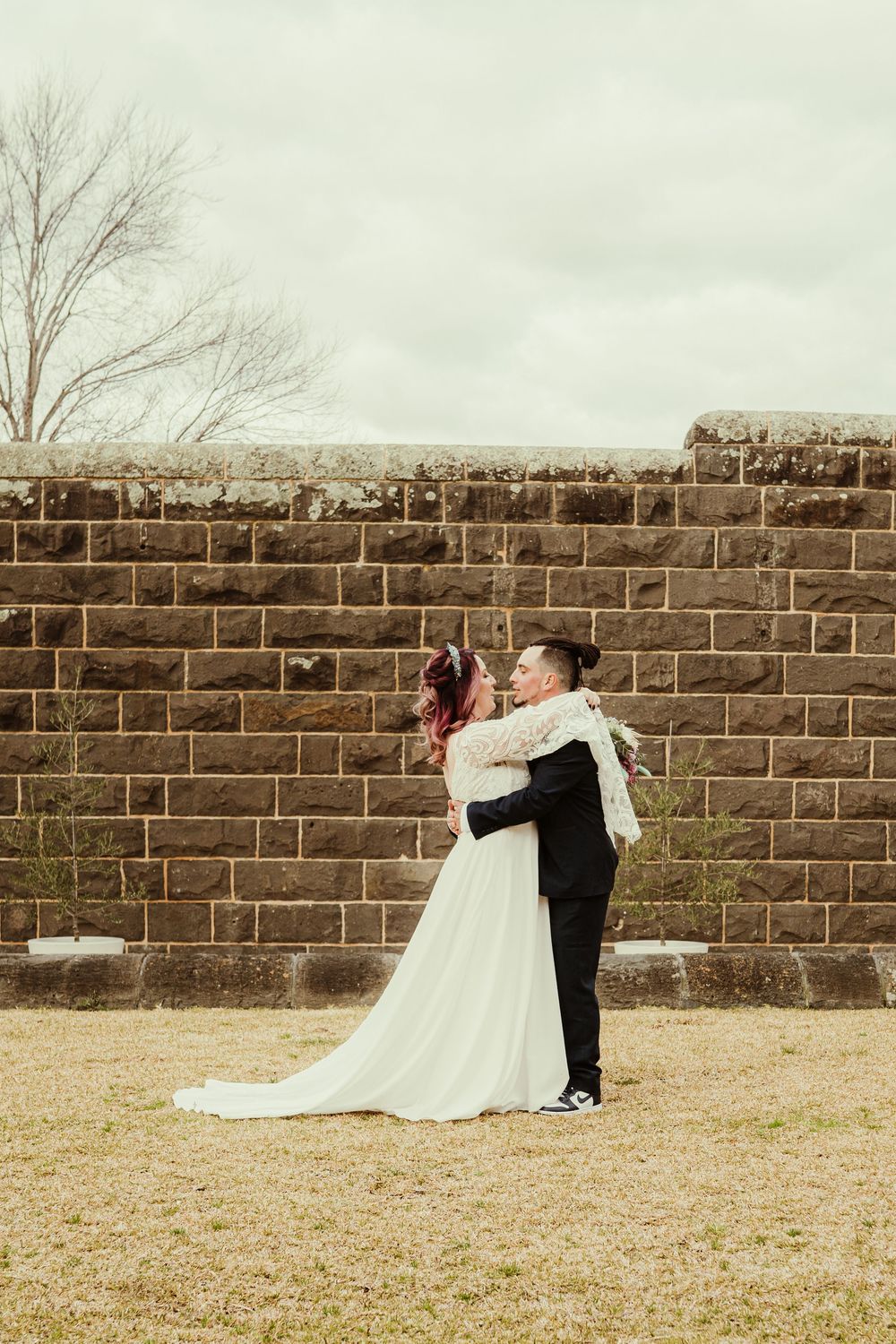 A wedding couple embraces in front of a rustic brick wall in a series of progressive snapshots.