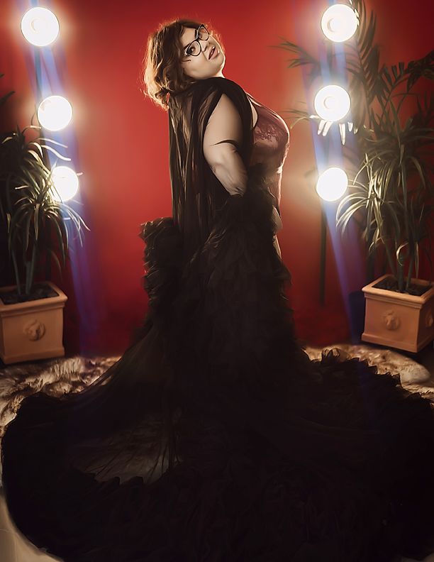 Dramatic boudoir photoshoot with moody red lighting and silhouette effects against a dark background.