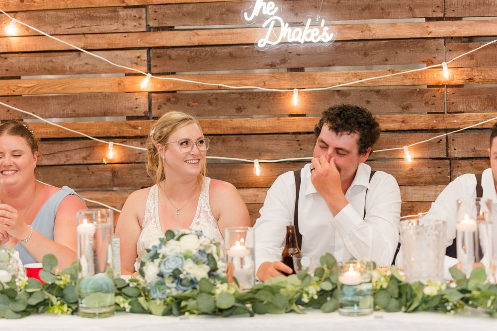 Rustic wedding reception venue with wooden walls decorated with string lights and greenery garlands.