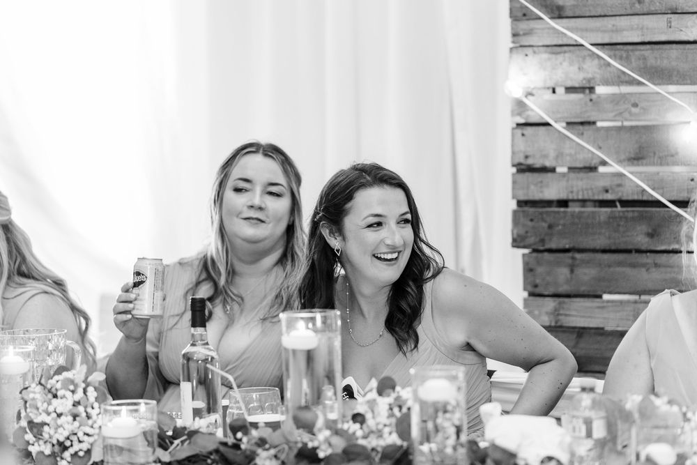 Two guests laughing and smiling together at an elegant wedding reception table with candlelight and decor.