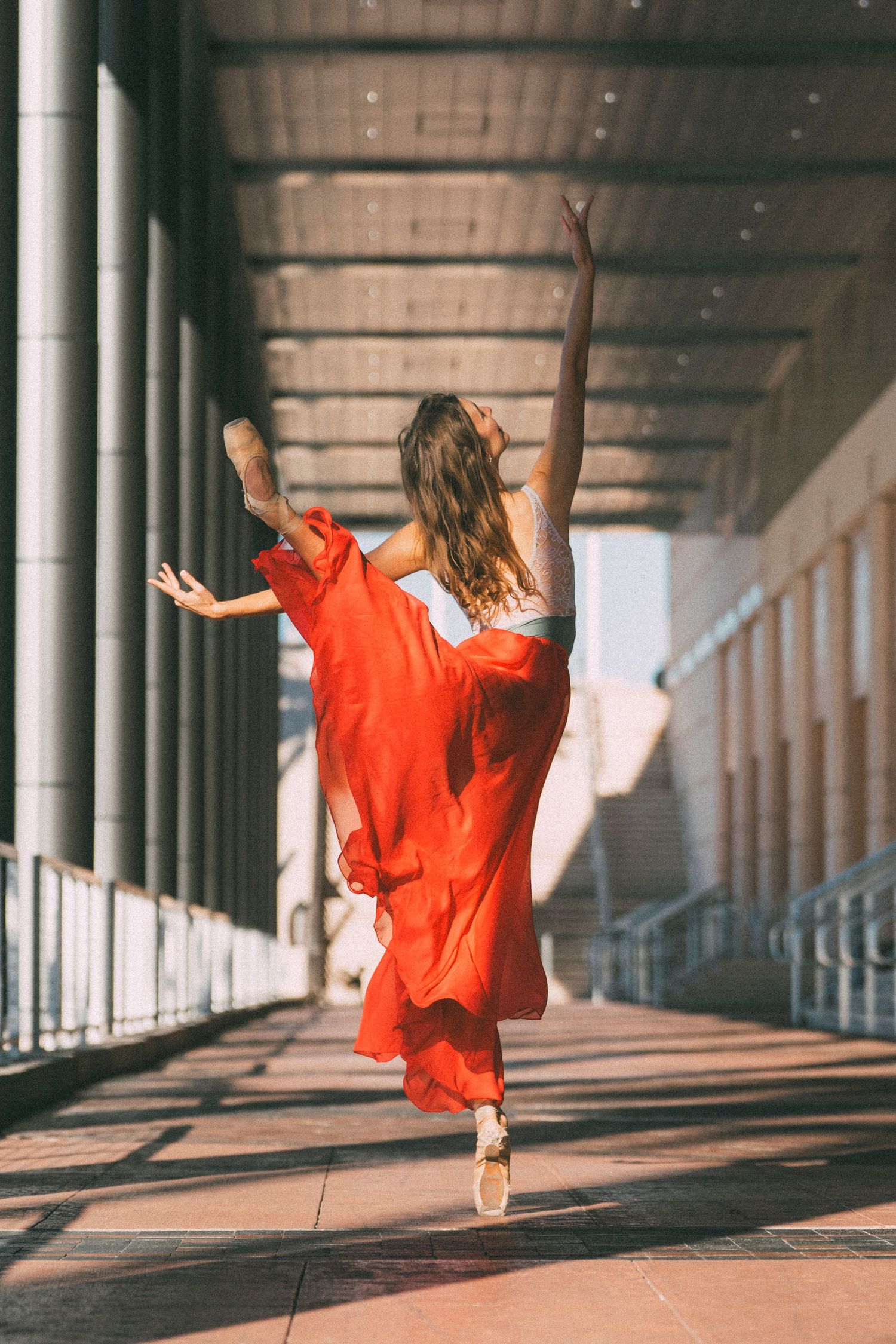 tampa ballet dance photography with ballerina in red skirt and leotard in pointe shoes extending her arm in the air