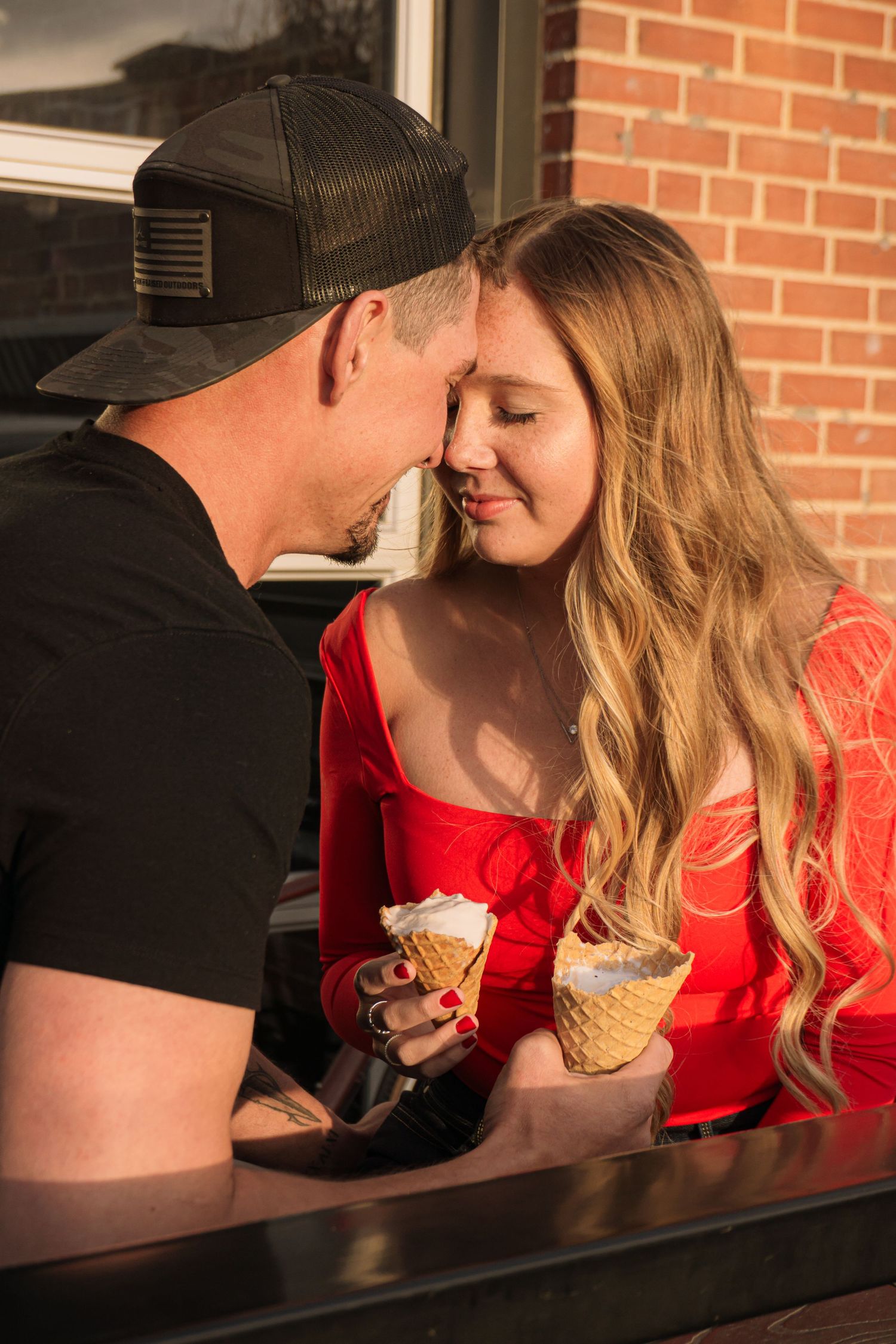 Colorado Springs Engagement Photographer. Couple outside and sitting down with ice cream in their hands and touching foreheads.