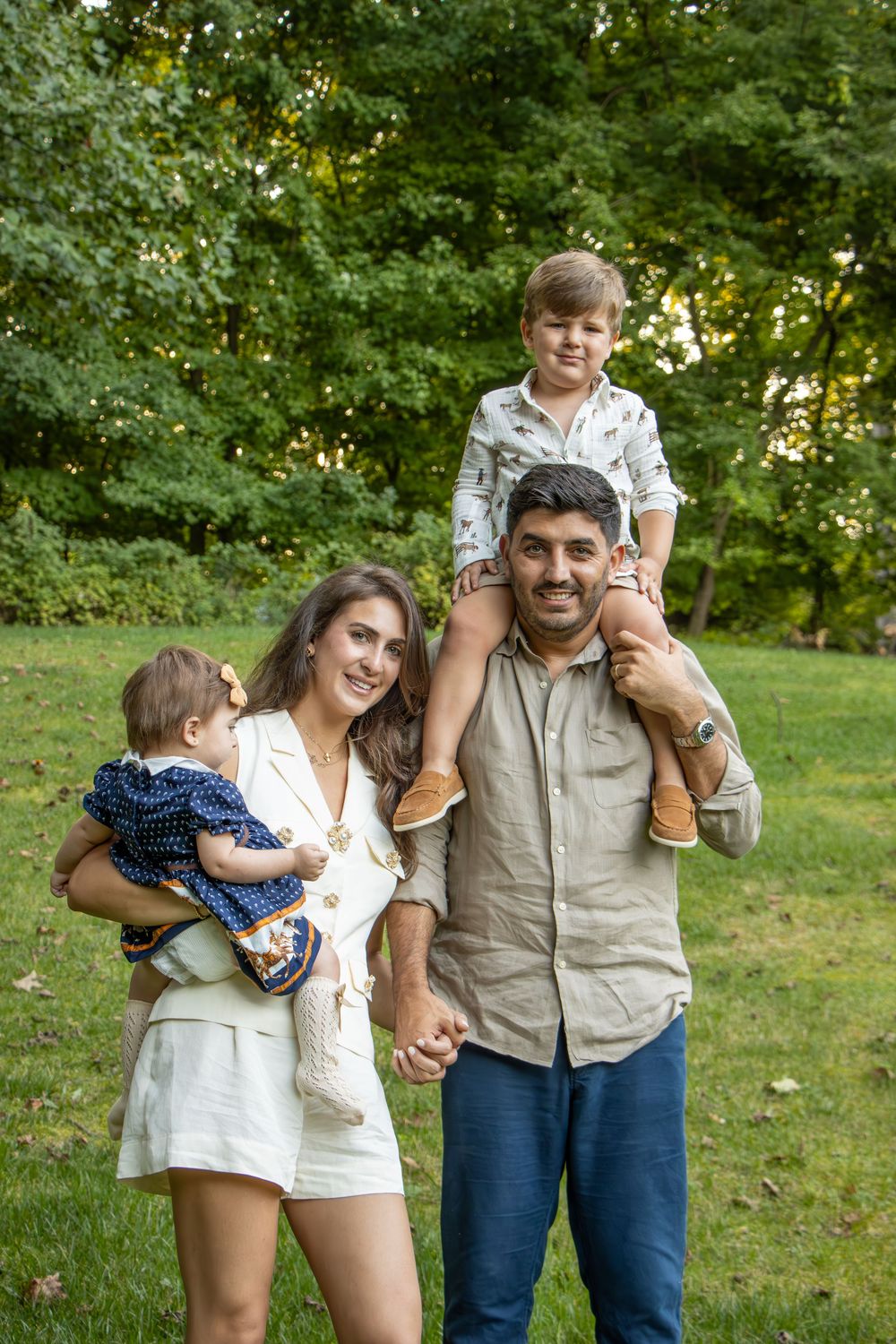 Happy family enjoying a summer day together outdoors in a lush green park setting.