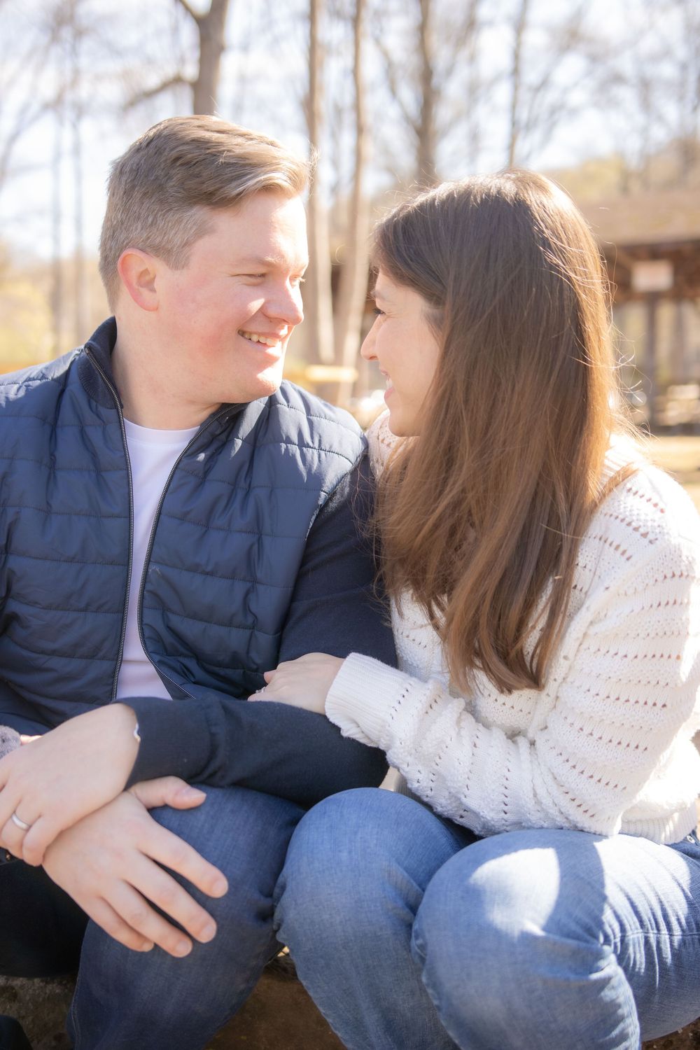 A couple sits together outdoors sharing an intimate moment in casual winter attire.